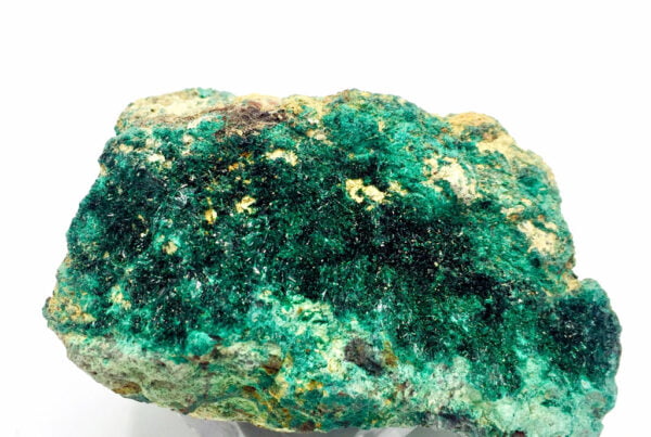 Primer plano de una piedra atacamita verde esmeralda, mostrando sus cristales prismáticos y su brillo vítreo característico