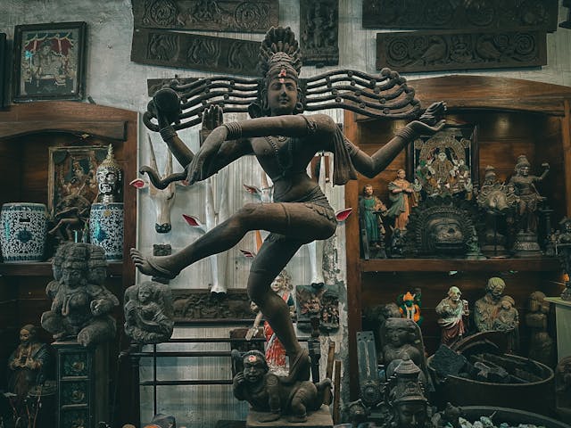 Interior de una tienda esotérica en Madrid, destacando una imponente estatua de Shiva Nataraja rodeada de otras figuras místicas y objetos espirituales, que invitan a explorar el mundo de la espiritualidad y la cultura oriental